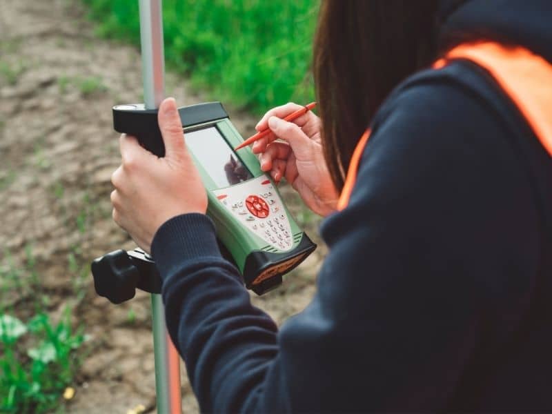 gps elevation survey data collection - Oxford Land Surveying Surveyor using a GPS data collector and survey rover to record precise ground elevation measurements for topographic mapping.
