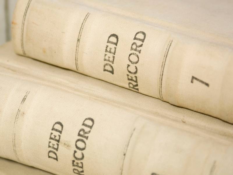 Property Survey Cost Older Deeds Oxford Alabama - Oxford Land Surveying Two old beige deed record volumes stacked on their sides, showing the spine text 'DEED RECORD'.